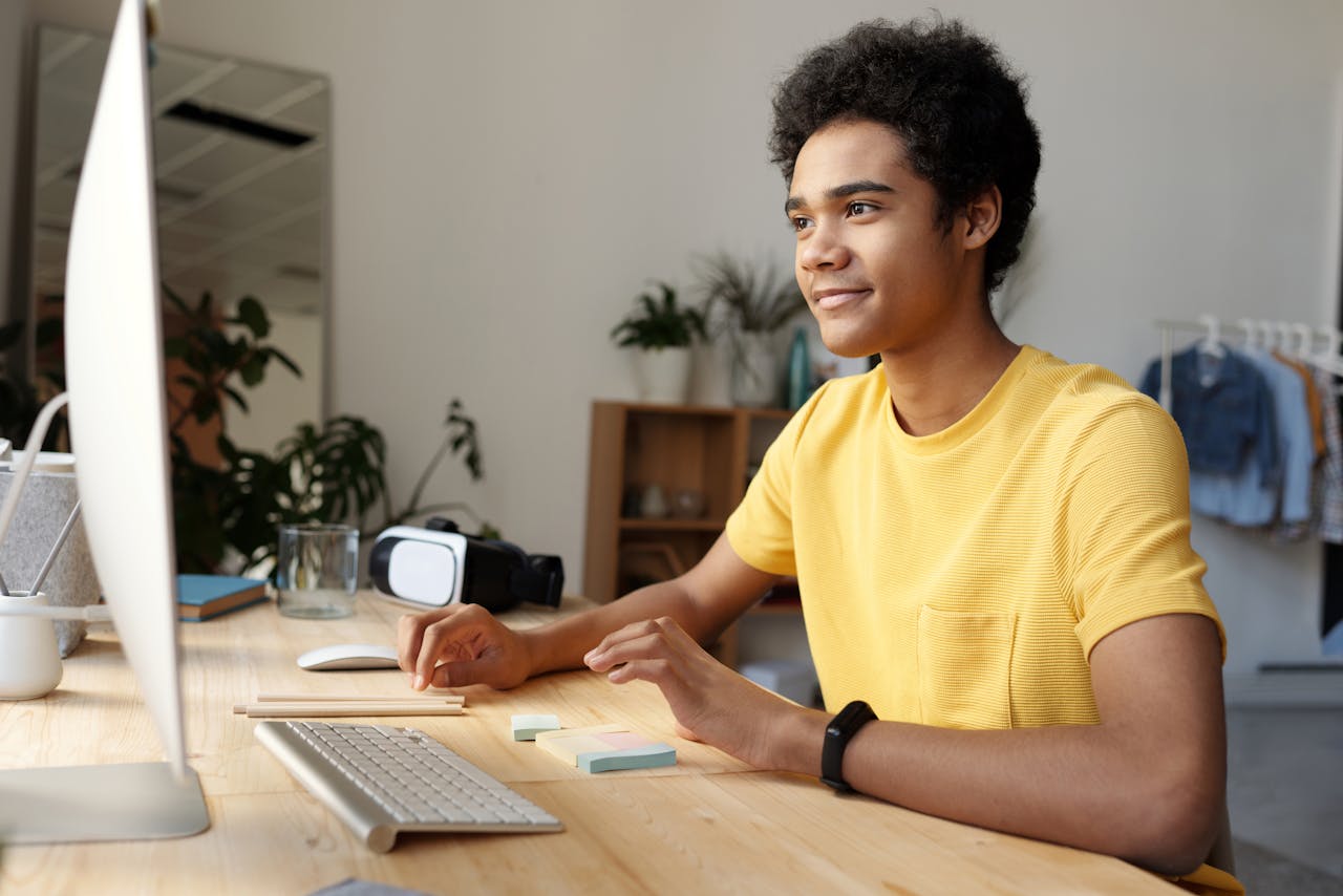 Mastering the First Impression: Your intriguing post title goes here Teenager smiling while studying online at home. Modern education setup with computer and VR headset.